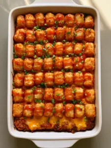 Tater Tot Meatloaf Casserole in a white ceramic baking dish on a grey countertop, showing the layered beef, melted cheese, and golden tots.